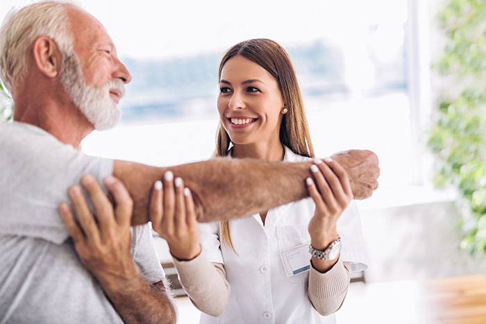 Woman helps older gentlemen with arm mobility.